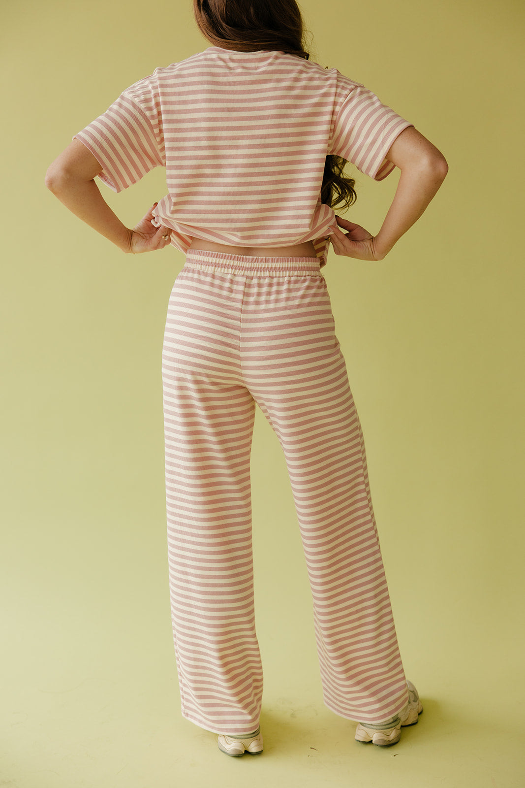 Person wearing a pink and white striped outfit on a yellow background