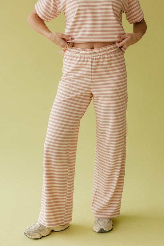 Person wearing pink and white striped pajama set on a yellow background