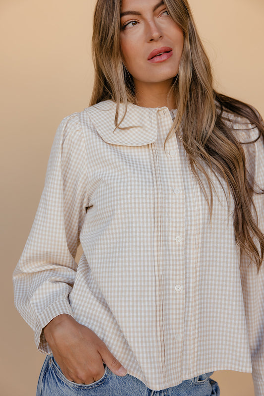 Woman wearing a checkered shirt against a beige background