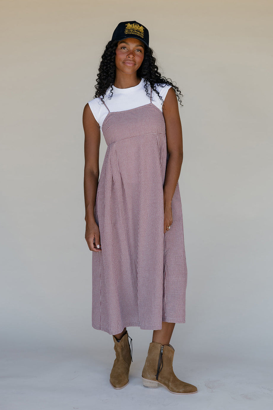 Woman wearing a pink dress over a white shirt, standing against a plain background