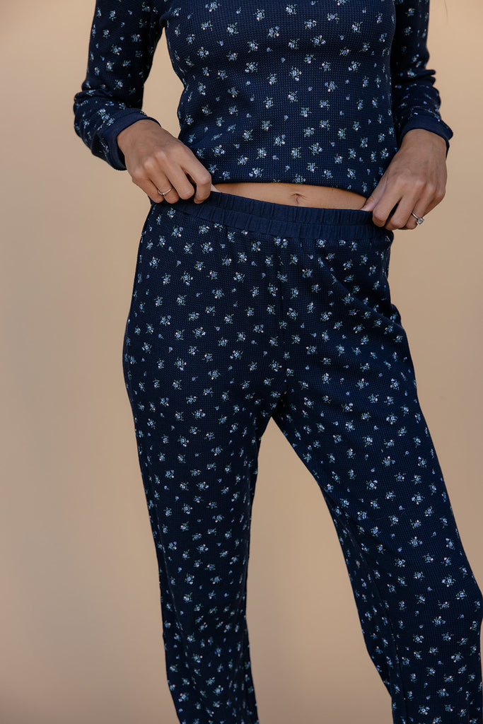 Person wearing a navy blue pajama set with a subtle pattern on a beige background