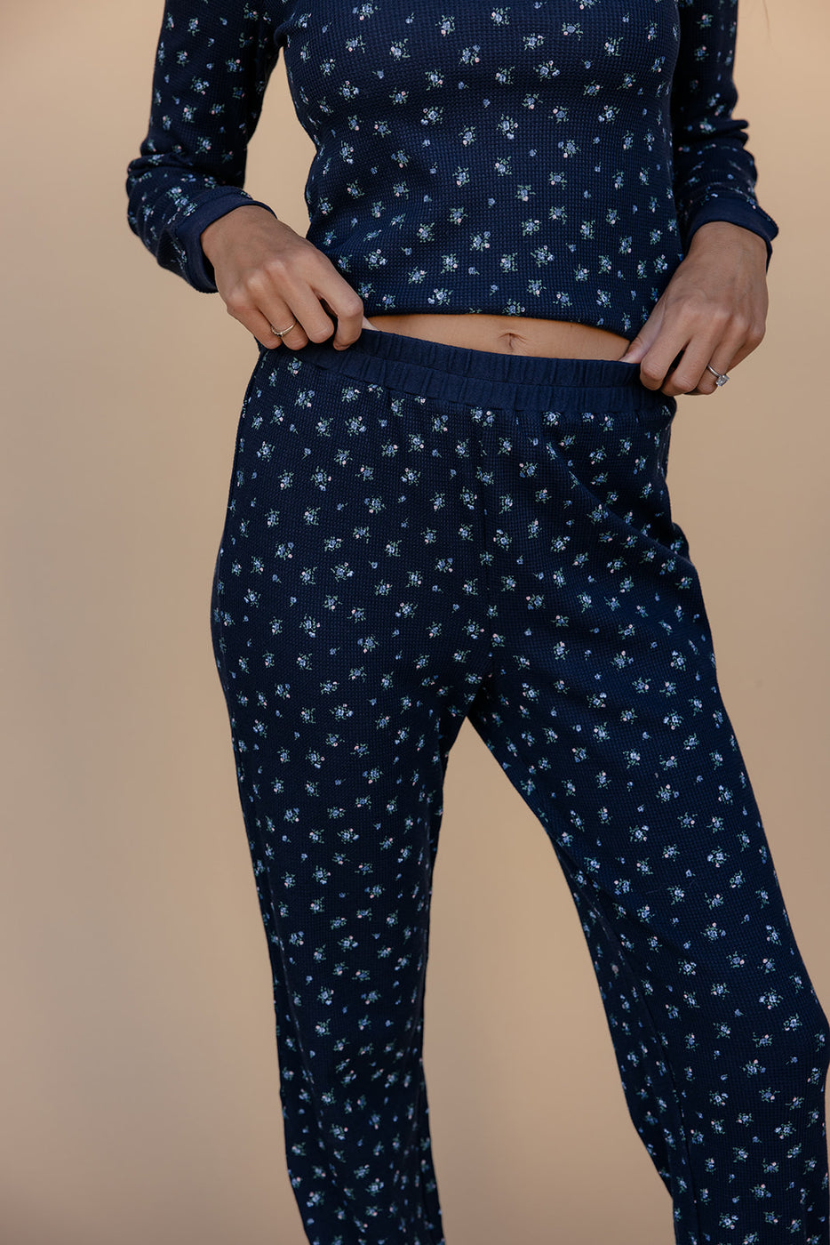 Person wearing a navy blue pajama set with a subtle pattern on a beige background