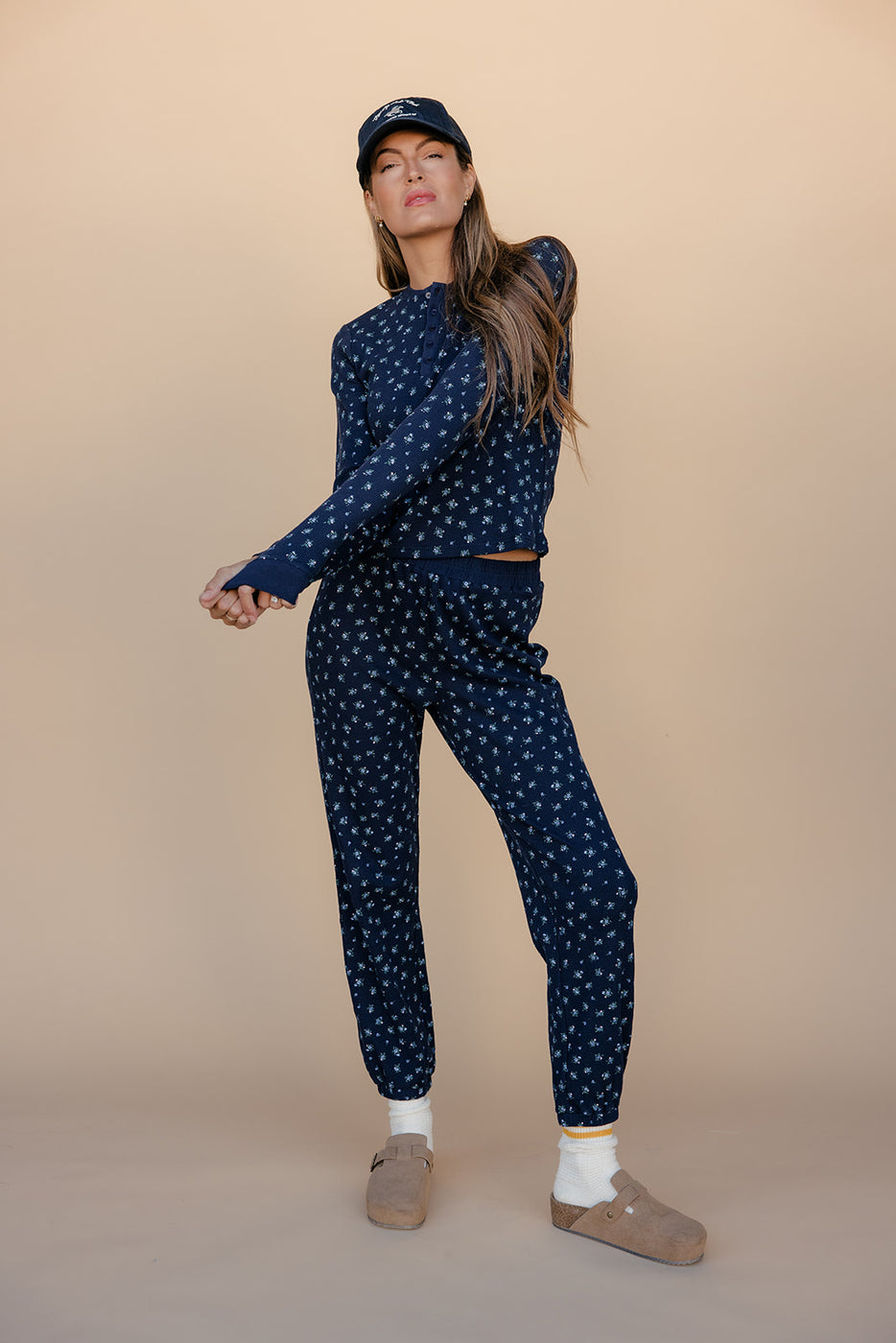 Woman wearing a navy blue polka dot outfit on a beige background
