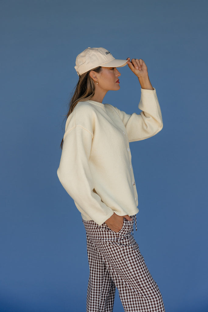 Person wearing a white sweater and checkered pants against a blue background