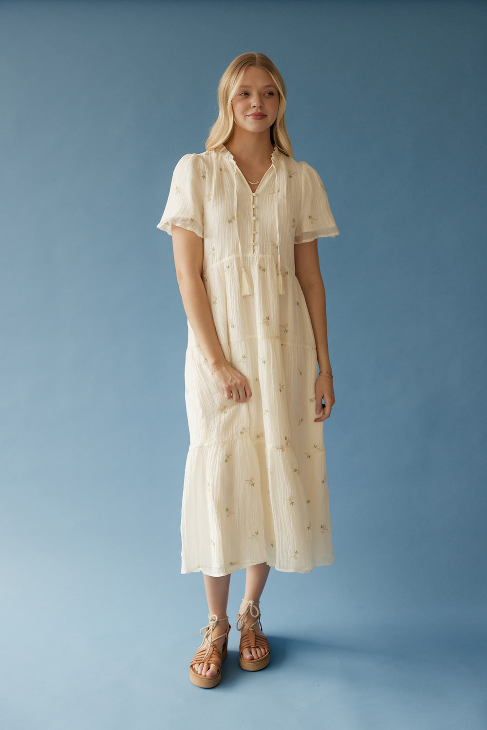Woman wearing a cream-colored dress against a blue background