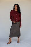 Woman wearing a burgundy button-up shirt and plaid skirt against a plain background