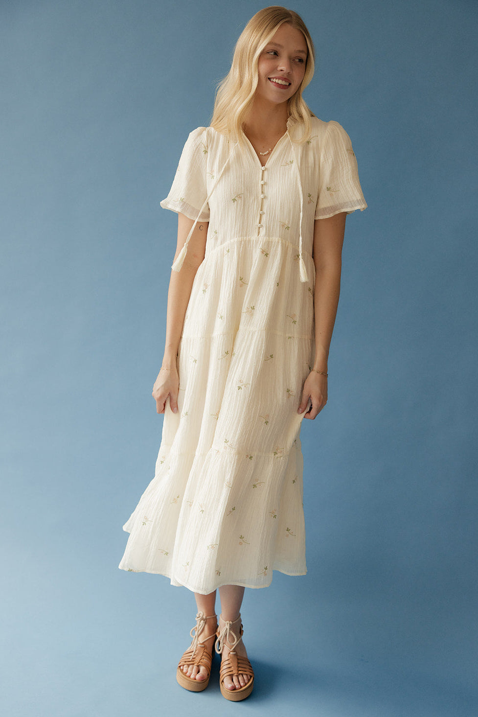 Woman wearing a beige dress against a blue background