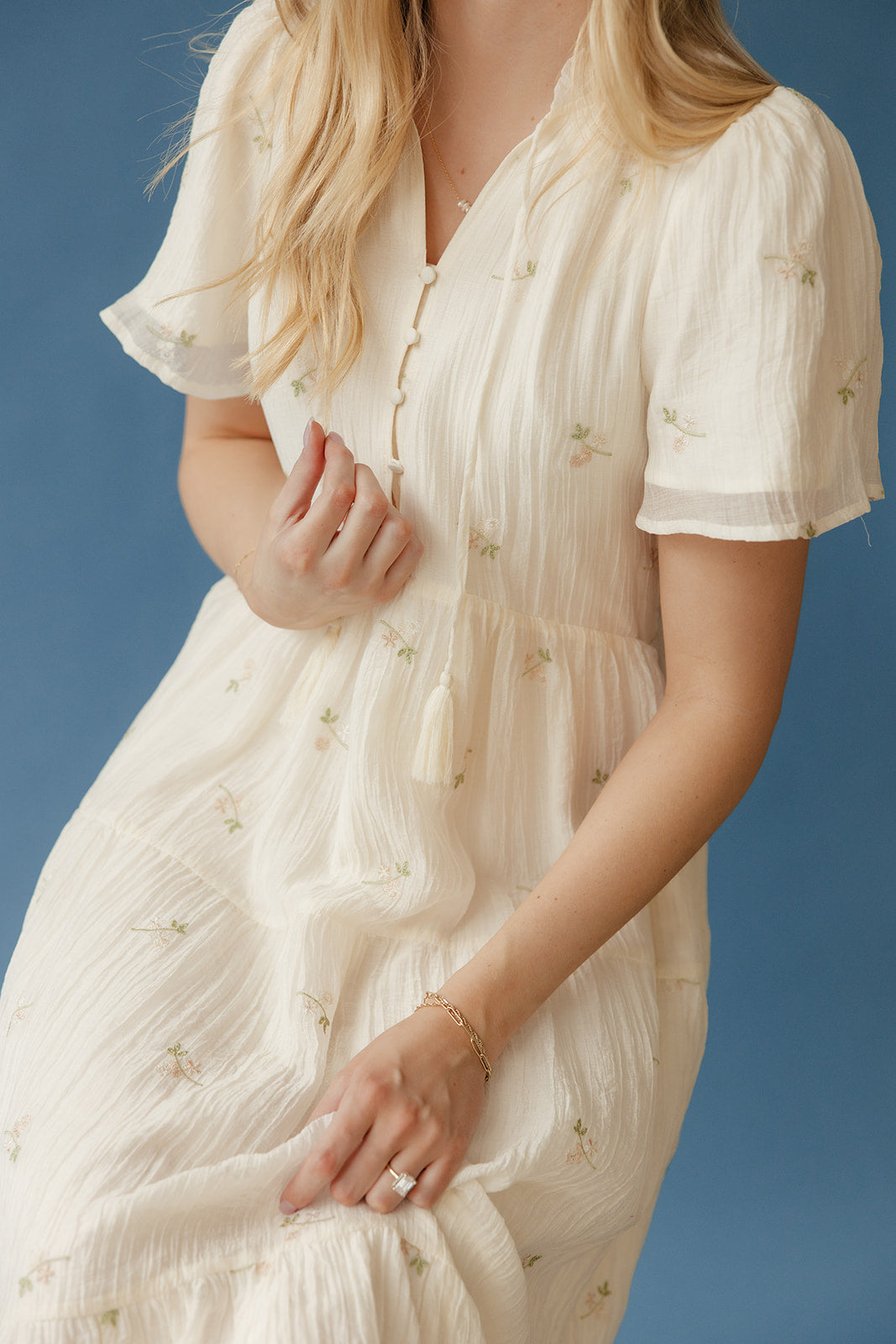 Woman wearing a white dress with short sleeves against a blue background
