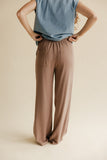 Person wearing a blue top and brown wide-leg pants on a beige background