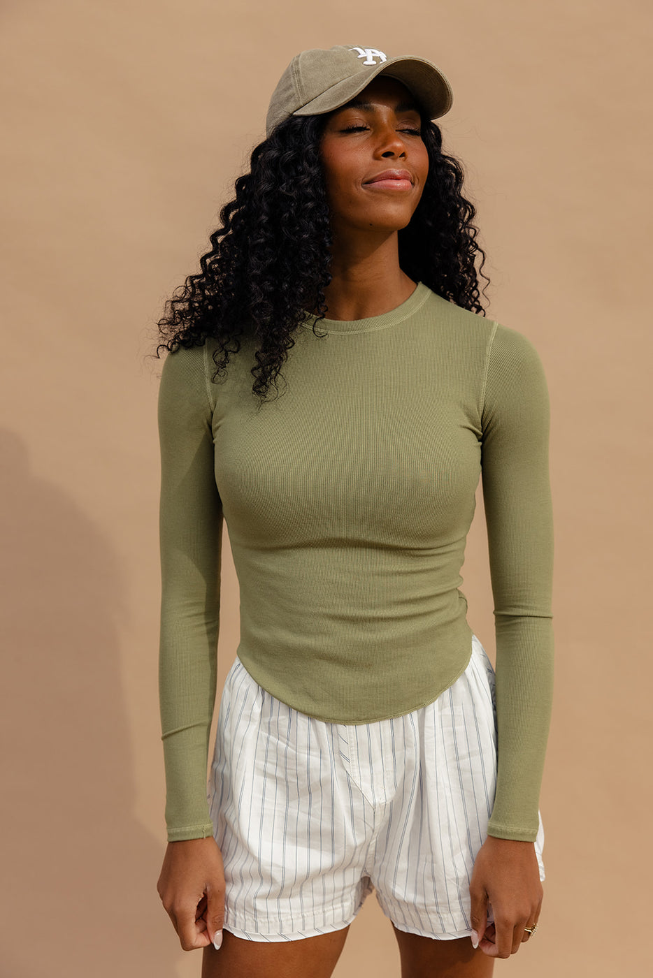 a woman with curly hair wearing a green shirt and white skirt