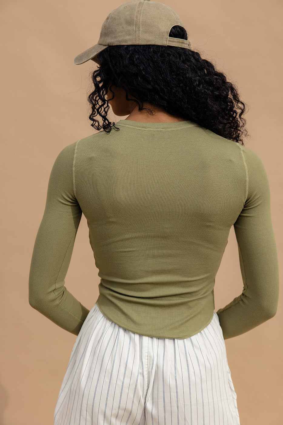 a woman with curly hair wearing a green shirt and white skirt