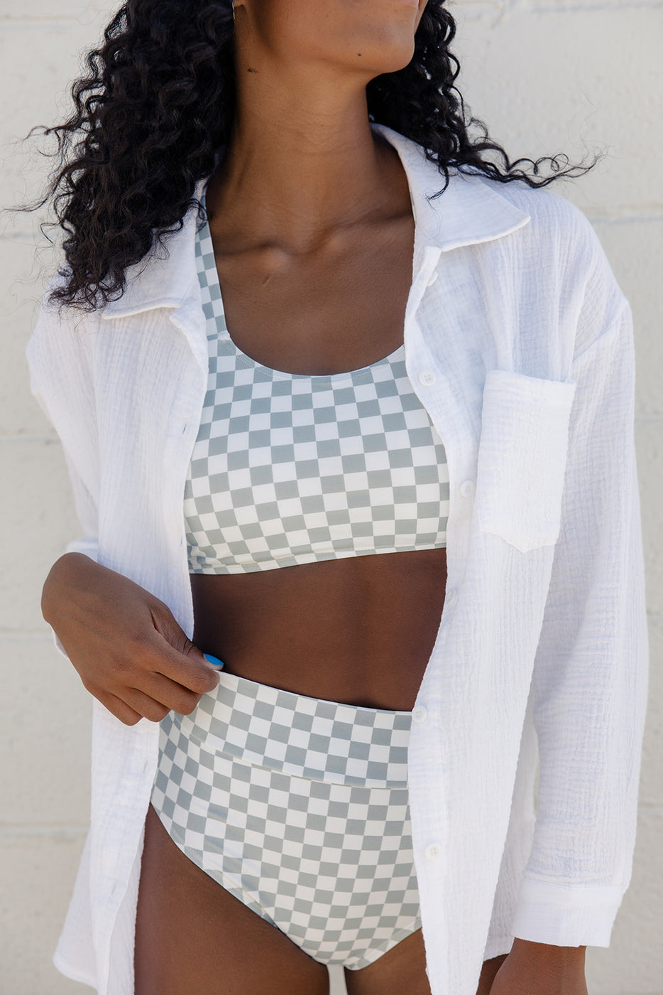 a woman wearing a white shirt and a checkered swimsuit