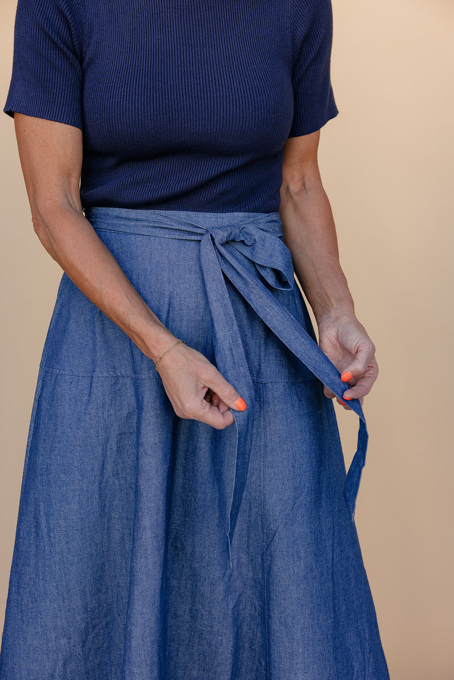 Person wearing a blue skirt with a plain background