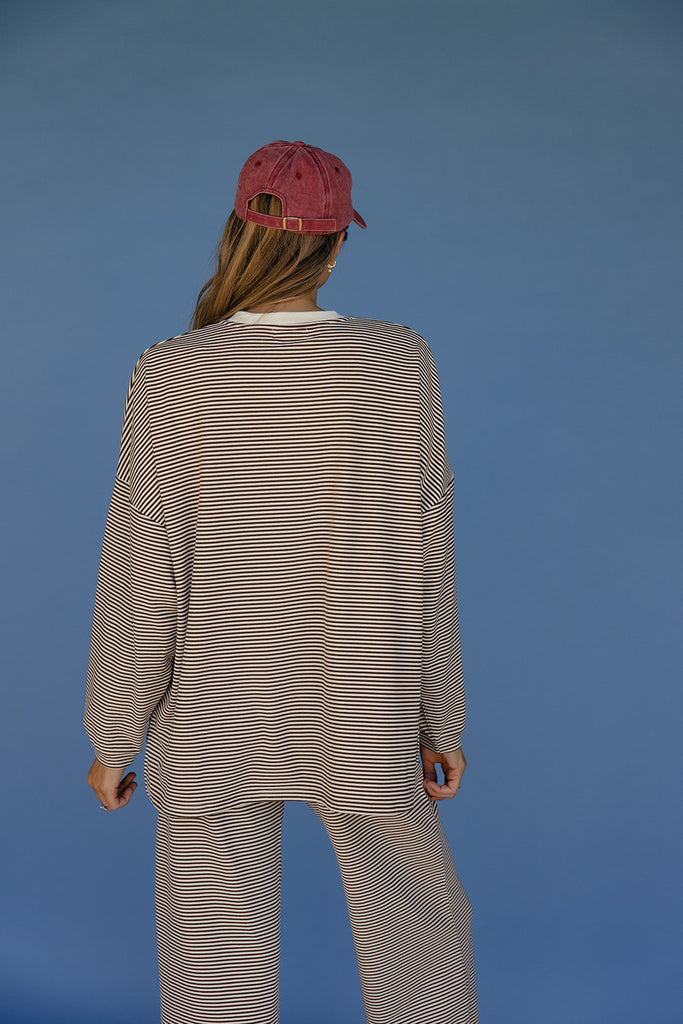 Person wearing a striped outfit and red cap on a blue background