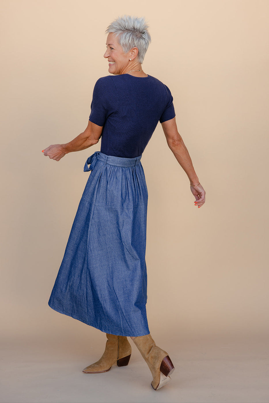 Woman wearing a blue dress and apron against a beige background