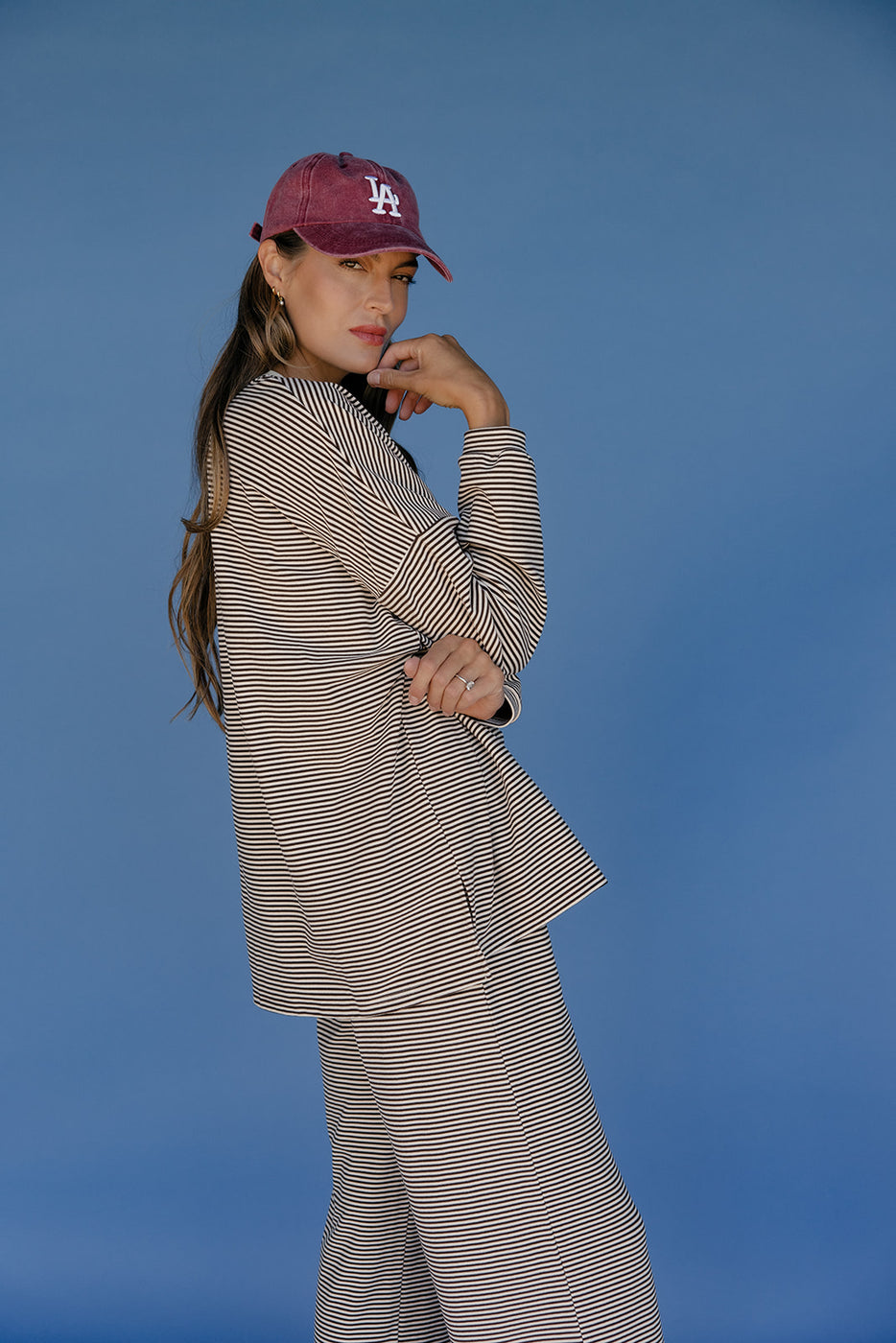 Woman wearing a striped suit and maroon cap against a blue background