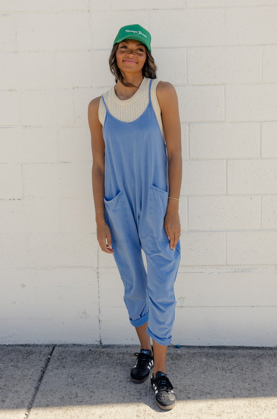 a woman in blue overalls standing in front of a white wall