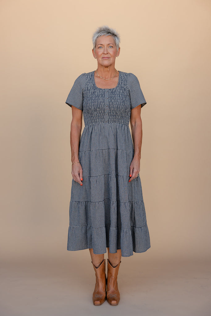 Woman wearing a blue checkered dress against a beige background