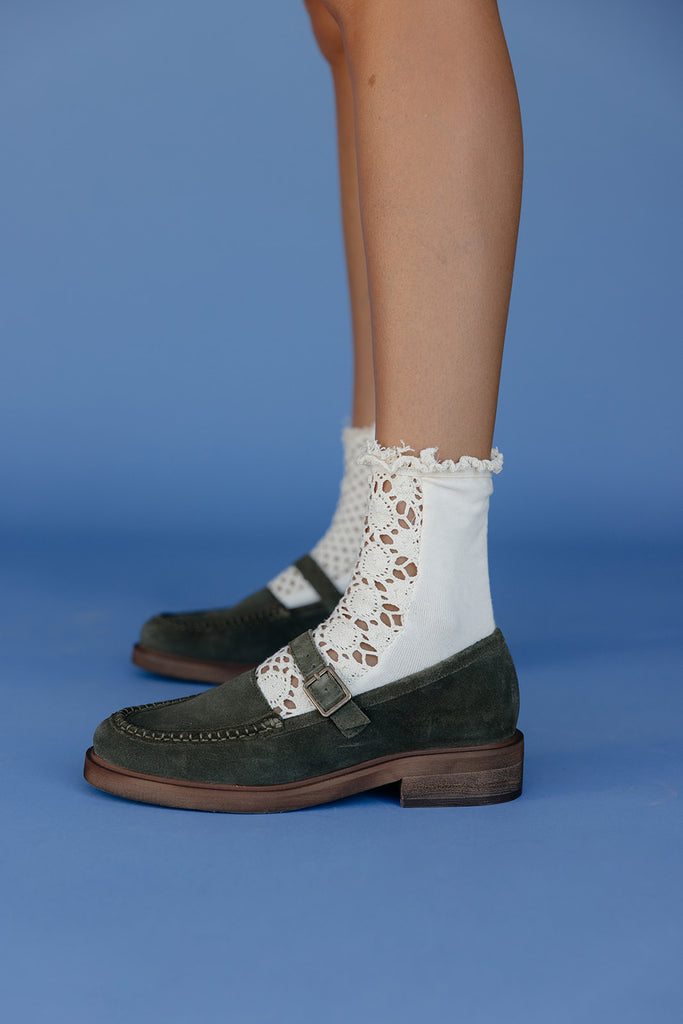 Green shoes with white socks featuring lace details on a blue background