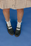 Person wearing white socks with black shoes on a blue background