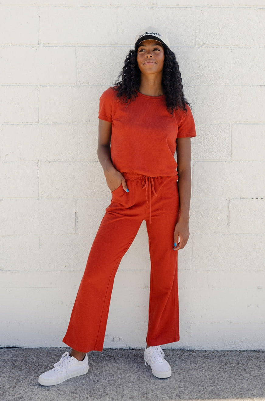 a woman in orange outfit standing against a white wall