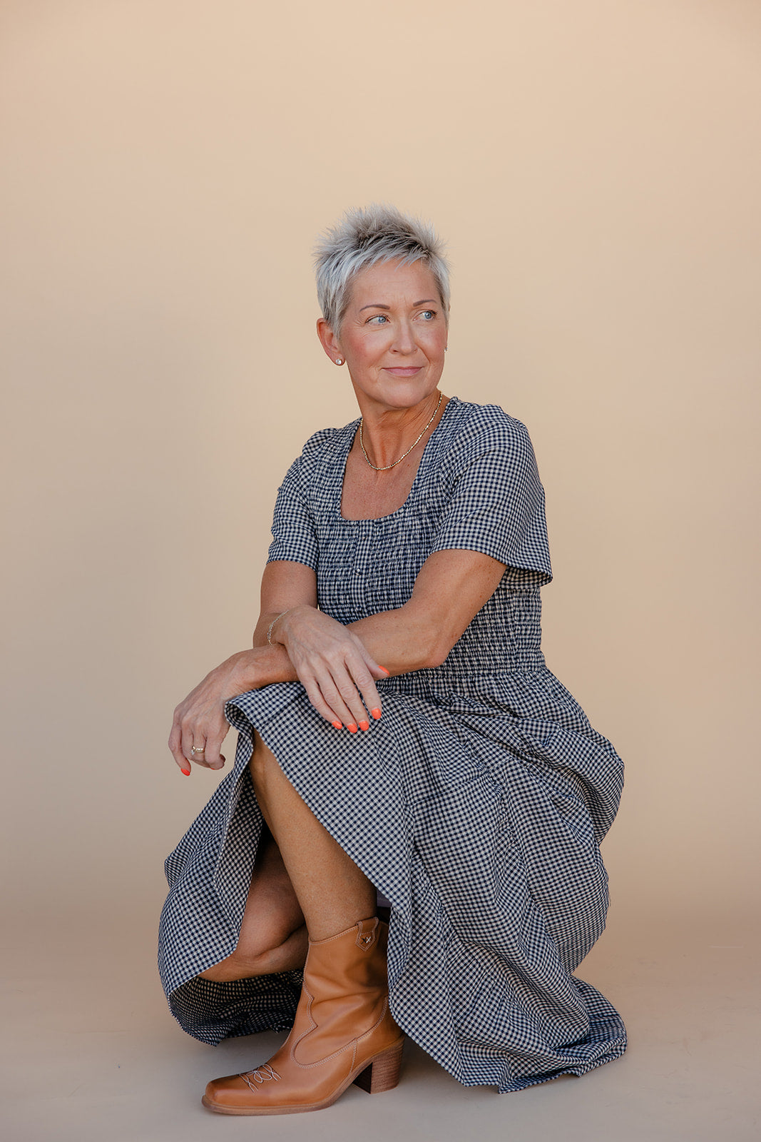 Woman wearing a blue checkered dress sitting on a beige background