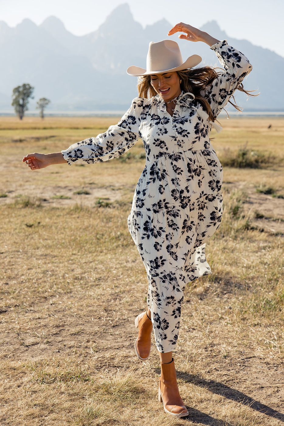 a woman in a dress and hat running in a field