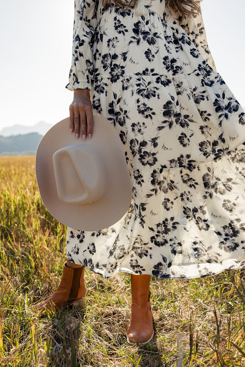 a woman wearing a dress and holding a hat