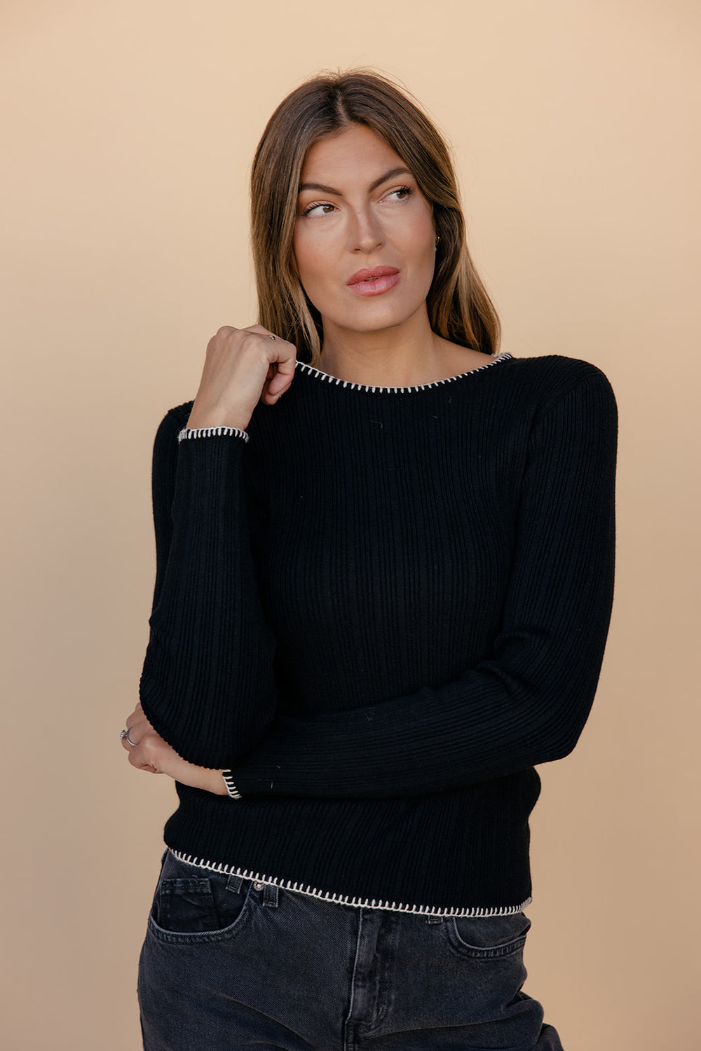 Woman wearing a black sweater with a beige background