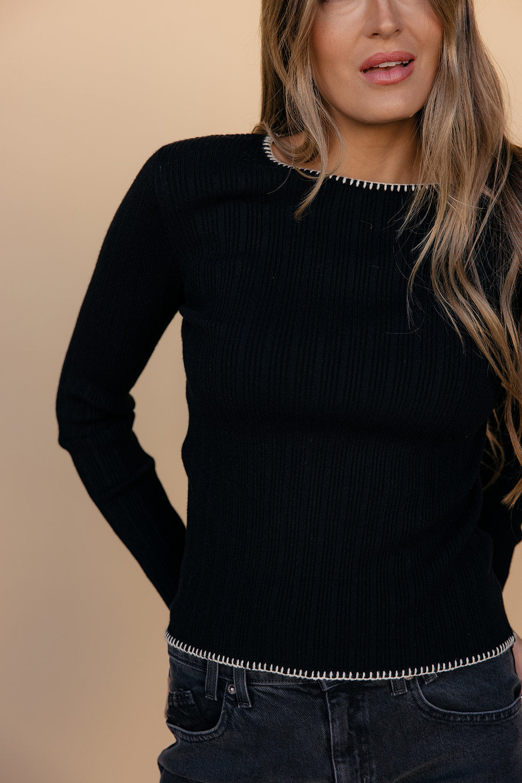 Person wearing a black sweater with a beige background