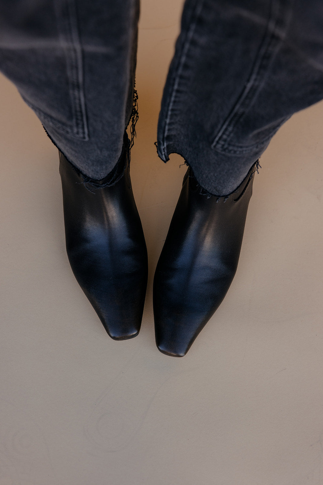Brown ankle boots worn with blue jeans on a neutral background