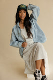 Woman wearing a denim jacket with a striped skirt set on a yellow background
