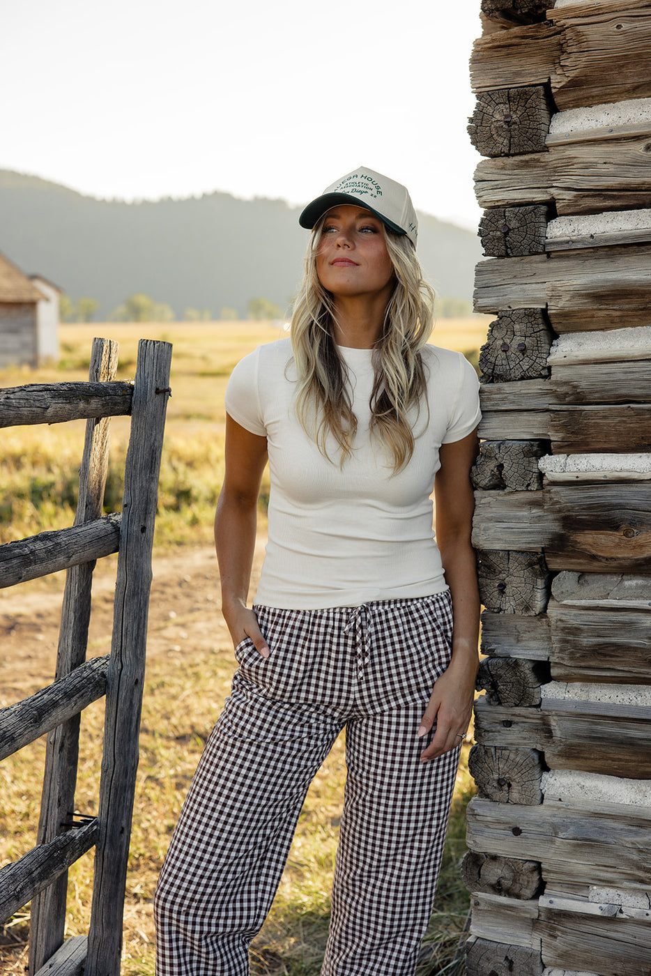 a woman standing next to a wooden fence