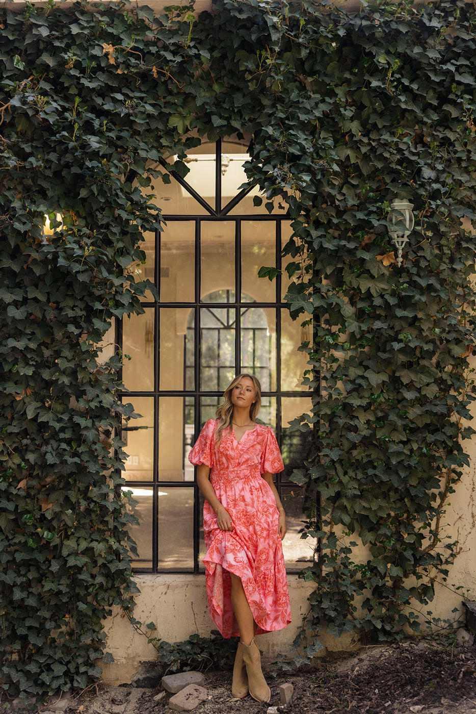 a woman in a pink dress standing in front of a window