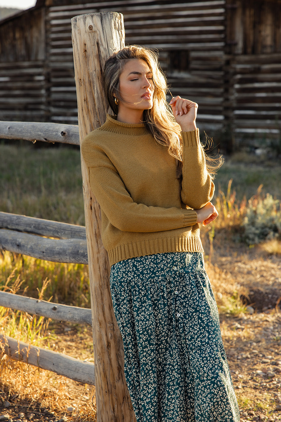 a woman leaning against a wooden post