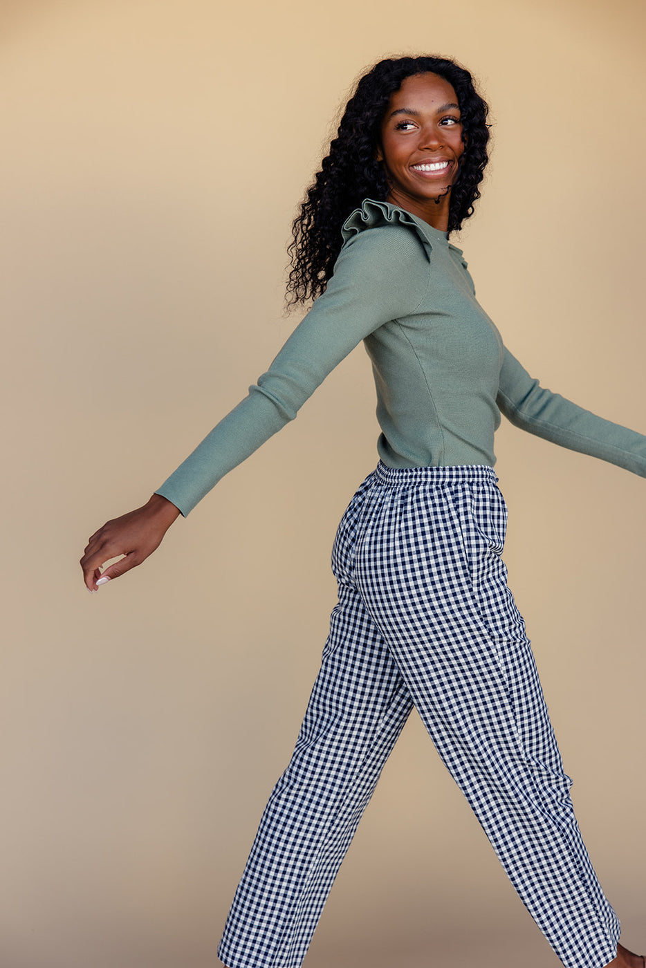 a woman wearing a green shirt and black and white checkered pants