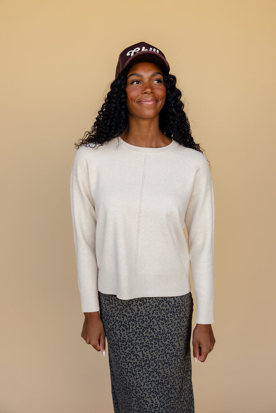 a woman in a white sweater and leopard print skirt