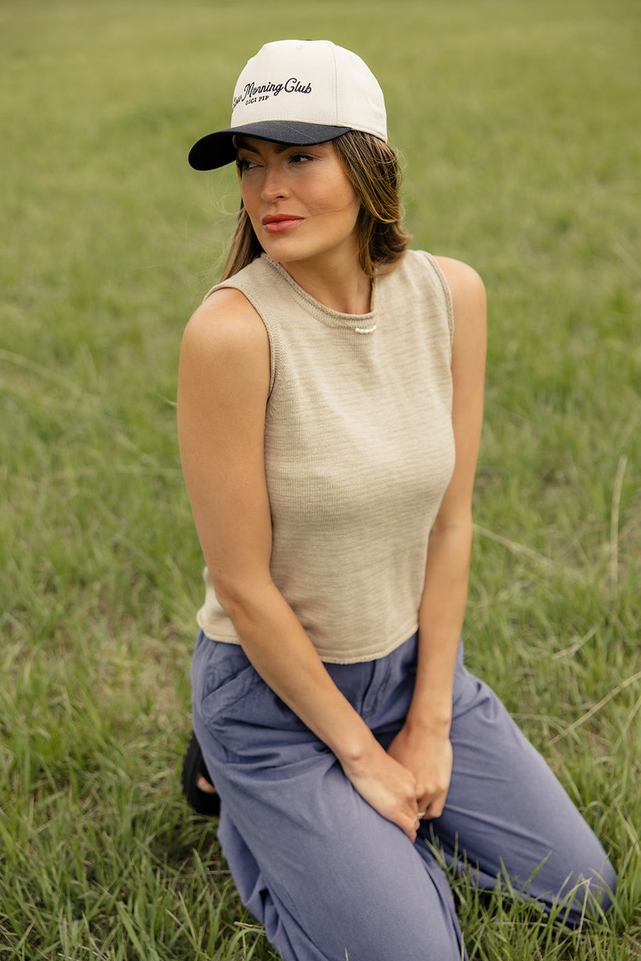 a woman in a hat sitting in grass