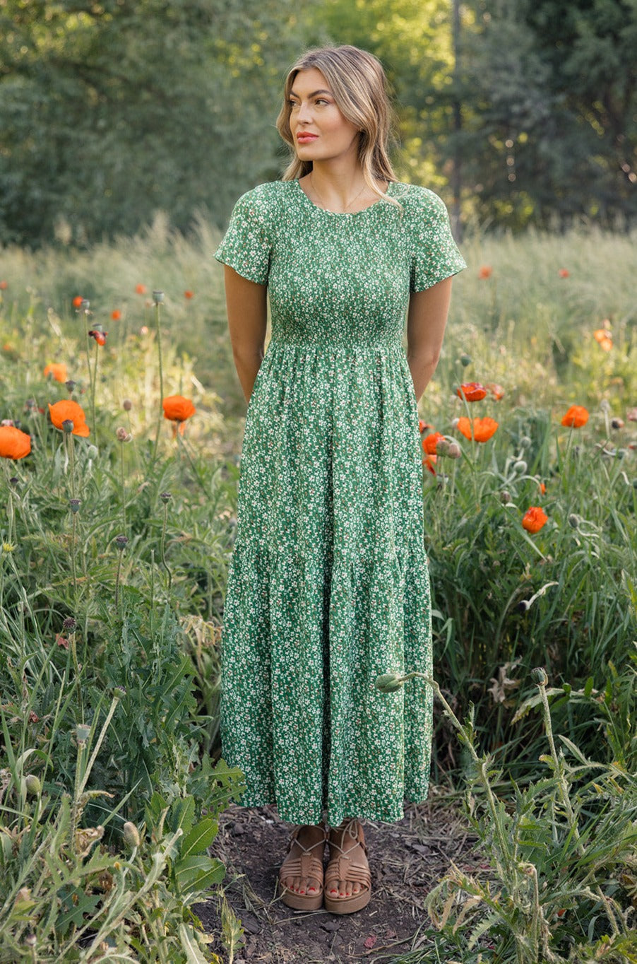 a woman in a green dress in a field of flowers