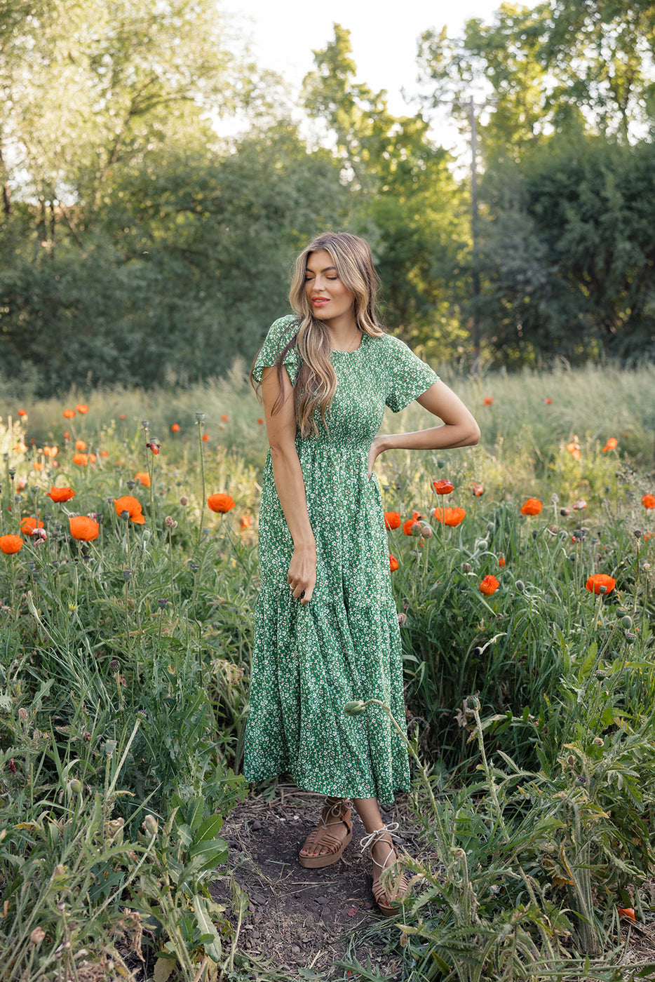 a woman in a green dress standing in a field of flowers