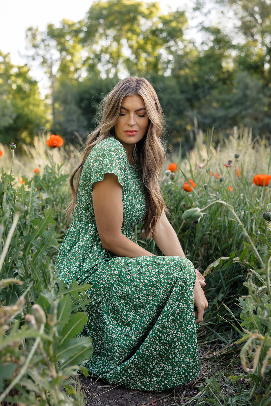 a woman sitting in a field of flowers