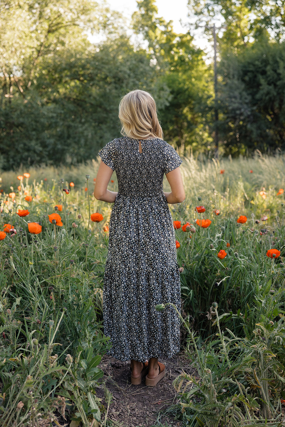 a woman in a dress standing in a field of flowers