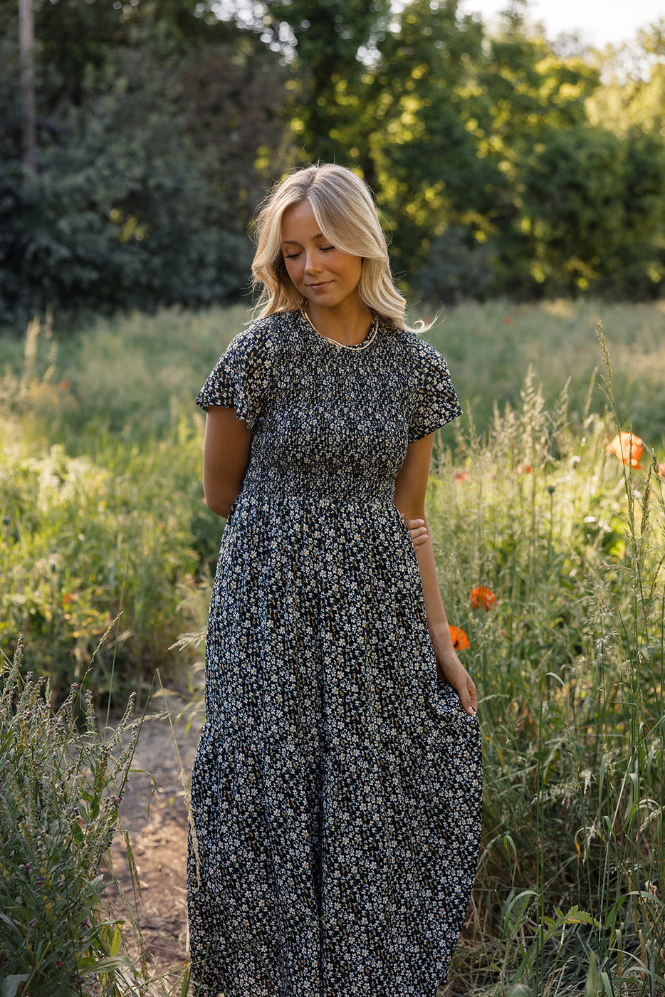 a woman in a dress standing in a field of flowers