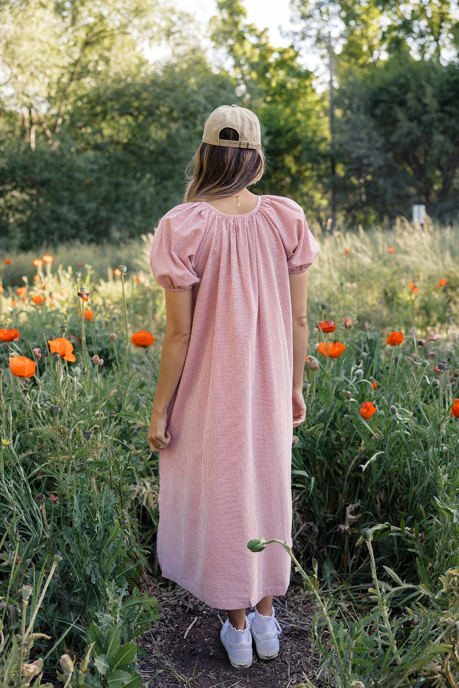 a woman in a red and white dress standing in a field of flowers