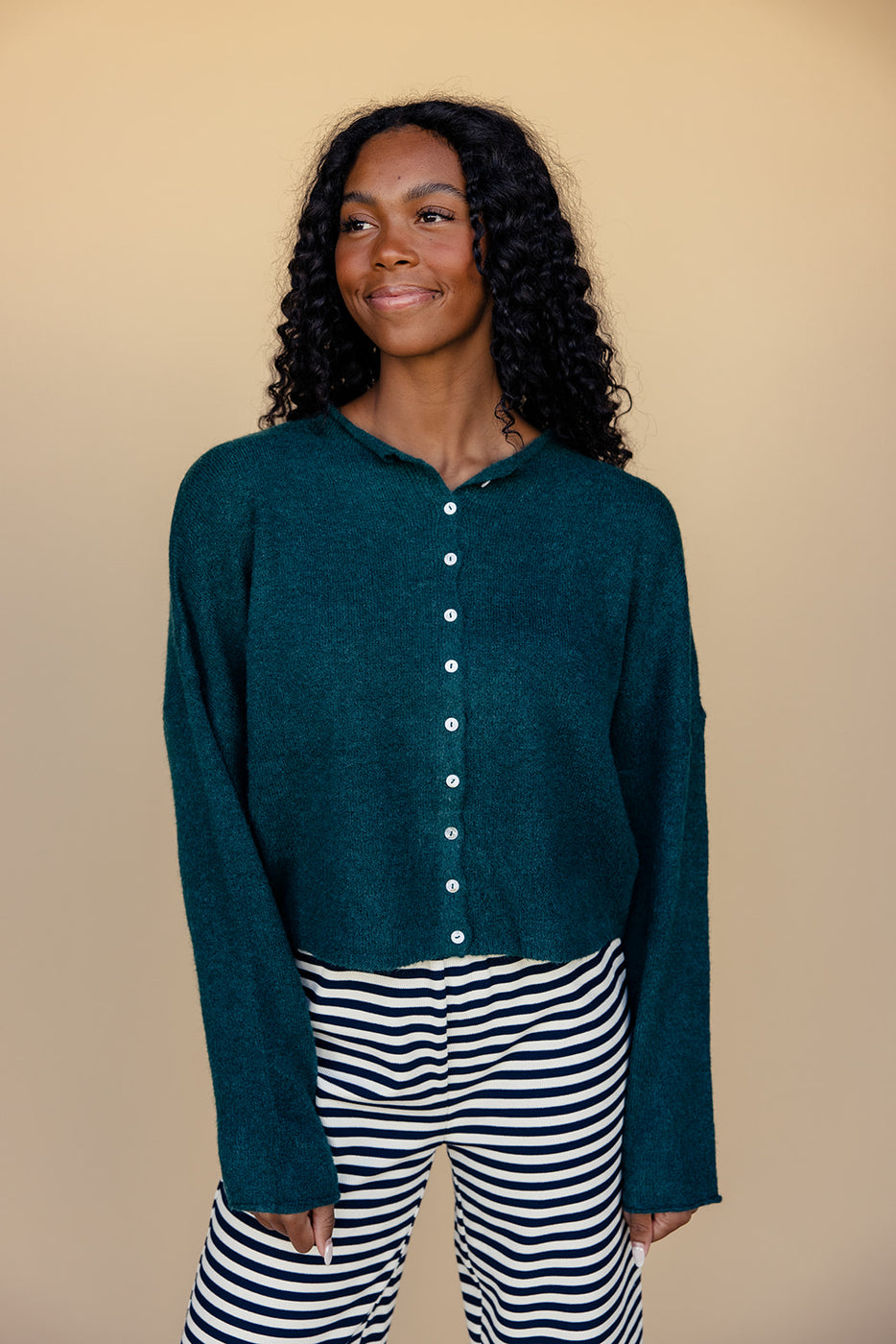 a woman smiling with a green sweater and striped skirt