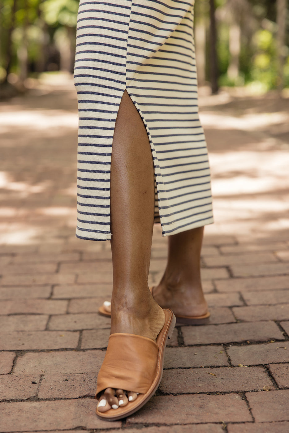 a person wearing a striped skirt and brown slippers