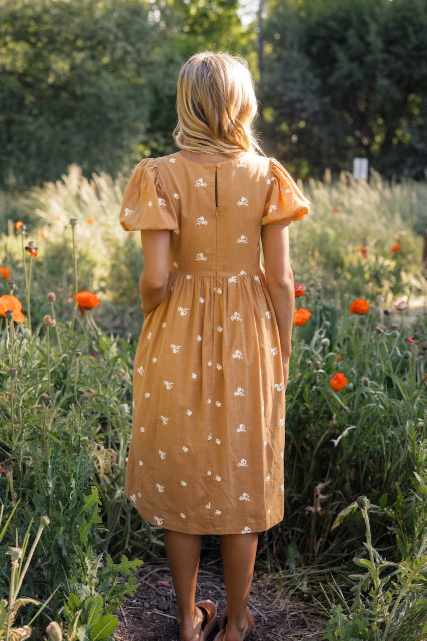 a woman in a dress standing in a field of flowers