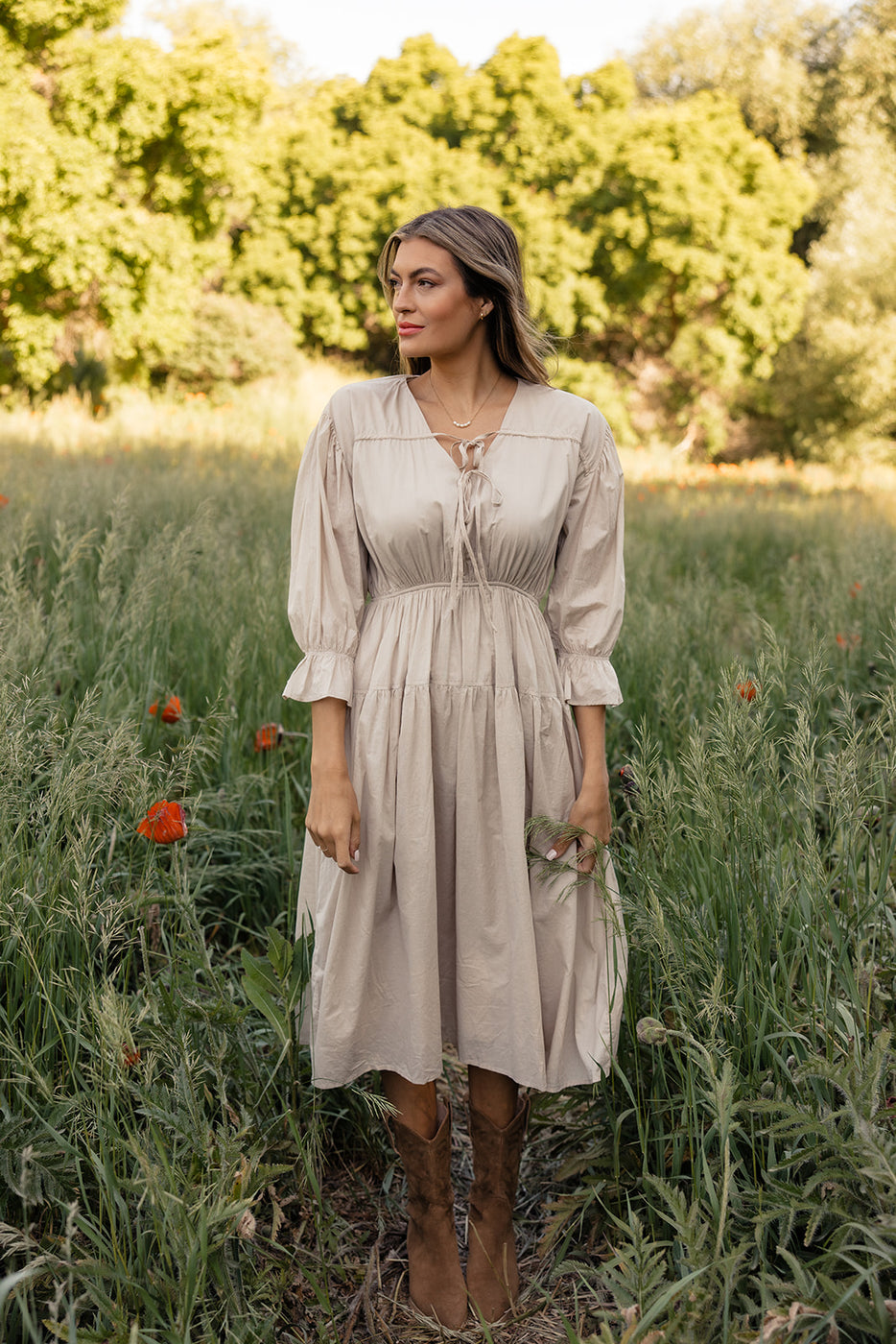 a woman in a dress standing in tall grass