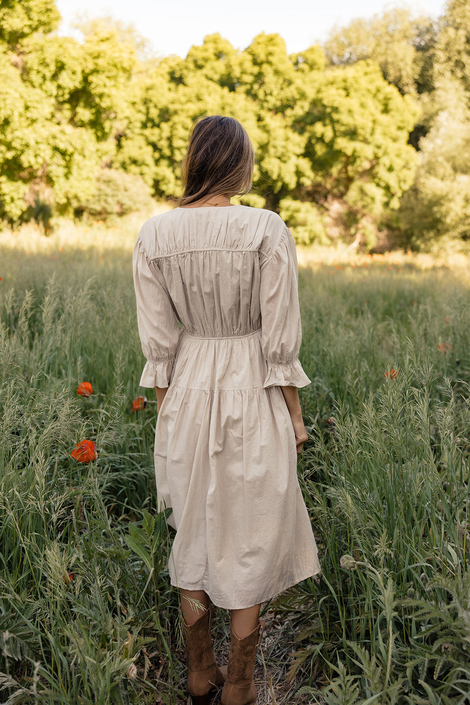 a woman in a dress standing in a field of tall grass