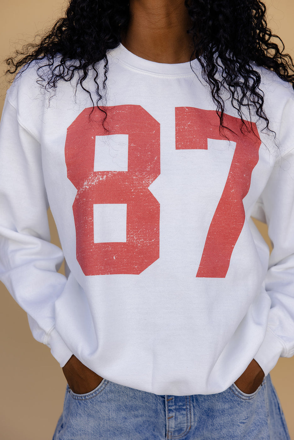 a person wearing a white sweatshirt with red numbers